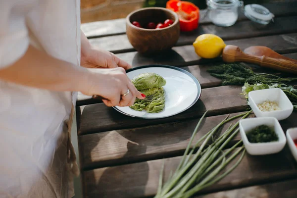 Avokadoyu çatalla ezen kadın elleri, guacamole pişiriyor. Piknik yaz yemekleri.