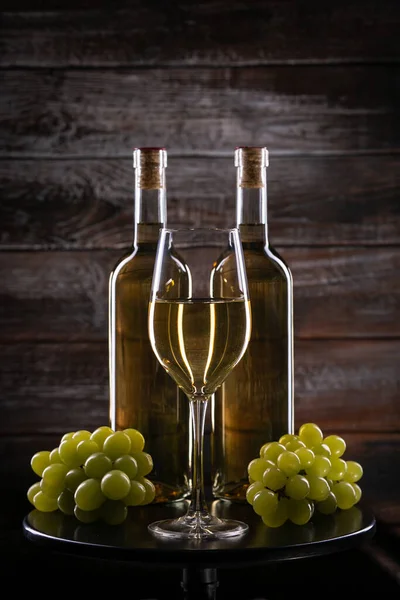 两只白色酒瓶 玻璃杯 木制底座上有葡萄 — 图库照片