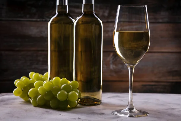 两个满满的白葡萄酒瓶子和酒瓶 酒瓶上有白布和木制底座上的葡萄 — 图库照片