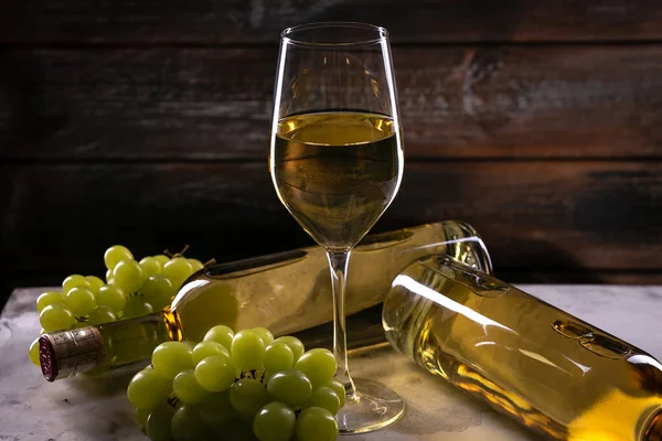 白葡萄酒杯 装有葡萄和两瓶葡萄酒 放在木制背景的白布上 — 图库照片