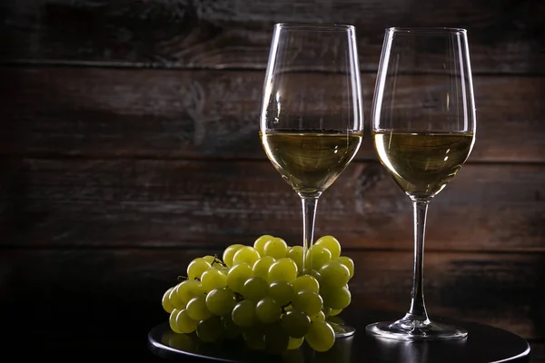 两个满满的白葡萄酒杯子 桌子上有葡萄 木制背景 — 图库照片