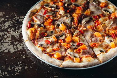 Eritilmiş peynirli, domatesli, biberli, mantarlı ve şifalı otlu İtalyan pizzasını yakın. Lezzetli sıcak pizza..