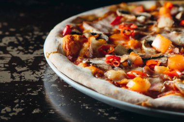 Eritilmiş peynirli, domatesli, biberli, mantarlı ve şifalı otlu İtalyan pizzasını yakın. Lezzetli sıcak pizza..
