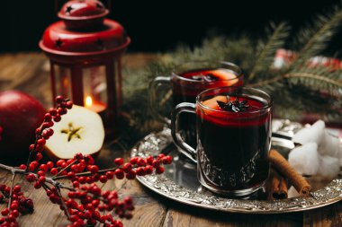 İçinde sıcak şarap, gümüş tepside tarçın, portakal ve kürk ağacı dalları olan iki bardak, yeni yıl natürmortu..