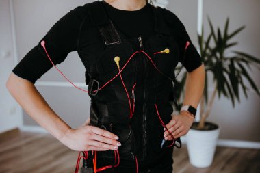 Woman in EMS electro stimulation suit with cables. clipart