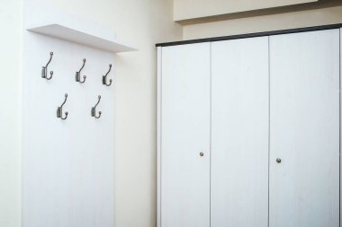 Askıları ve dolabı olan beyaz koridor dolabı. Minimalist tasarım mobilyaları.
