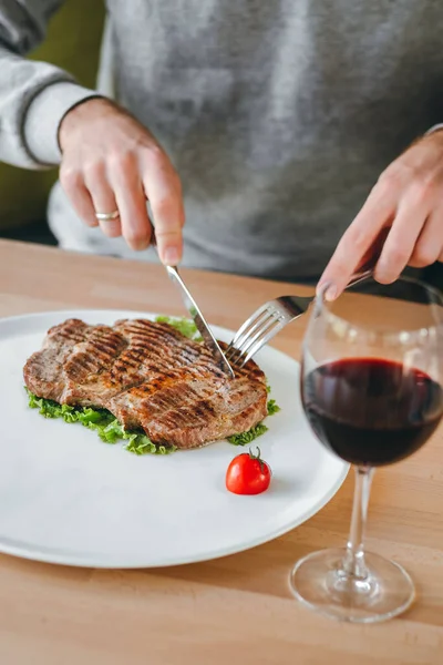 肉のグリルステーキ サラダ チェリートマトを赤ワイングラスで食べる男の手 — ストック写真