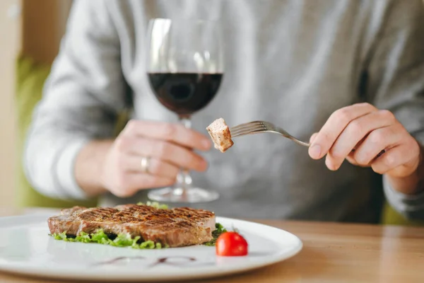 肉のグリルステーキ サラダ チェリートマトを赤ワイングラスで食べる男の手 — ストック写真