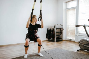 ATS elektro uyarı giysisi içinde TRX kullanan bir kadın..