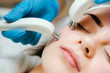 Kadının terapistten tahrik edici bir yüz tedavisi gördüğü yakın plan fotoğraf. Mikro akım terapisi.