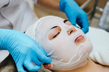 Yüz soyma maskesi, kaplıca güzellik tedavisi, cilt bakımı. Güzellik salonunda güzellik uzmanı bir kadının yüz bakımını alıyor..