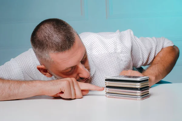 Man looking at and touching pile of phones. Smartphones collection of a businessman.