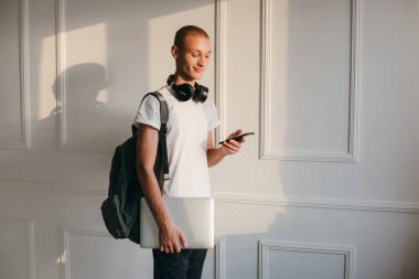 Mutlu gülümseyen öğrenci dizüstü bilgisayar tutuyor, beyaz arka planda izole edilmiş.