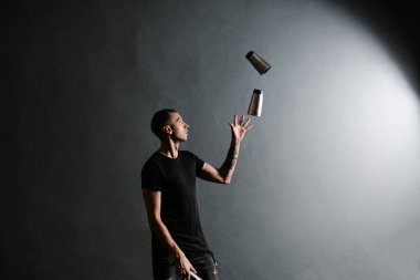 Barmen titretici ile hokkabazlık ve gri arka planda izole kokteyl yapar