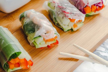 Lezzetli Asya yemeği. Karides ve sebzeli taze börek ve farklı soslarla servis edilen tahta tabakta servis edilen pirzola çubukları..