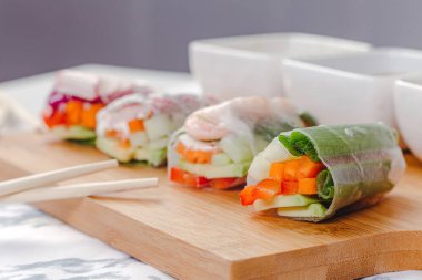 Lezzetli Asya yemeği. Karides ve sebzeli taze börek ve farklı soslarla servis edilen tahta tabakta servis edilen pirzola çubukları..