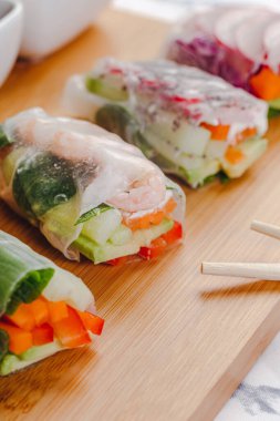 Lezzetli Asya yemeği. Karides ve sebzeli taze börek ve farklı soslarla servis edilen tahta tabakta servis edilen pirzola çubukları..