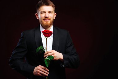 Yakışıklı delikanlı gülümsüyor, randevuya hazırlanıyor, kırmızı gül tutuyor..