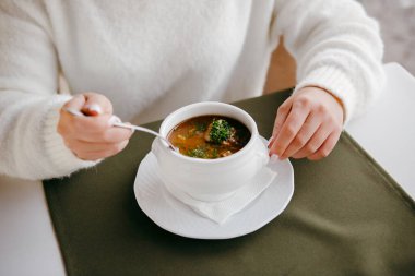 Restoran yemeği. Beyaz kazaklı, geleneksel Macar Gulaş çorbası içen bir kadın..
