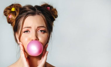 Genç ve güzel bir kadın sakız üflüyor. Saç stili olan bir kızın oyuncu portresi. Neşeli yaz kızı.