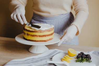 Mutfakta karantina sırasında meyveli, böğürtlenli, limonlu ve nane arkaplanlı limonlu kek pişiren bir ev kadını. Ev yapımı organik limonlu kek tarifi. Evde yemek pişirmek..