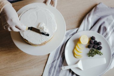 Karantina sırasında üzerinde meyve, böğürtlen, limon ve nane olan limonlu kek pişiren bir ev hanımı manzarası. Ev yapımı limonlu kek tarifi. Evde yemek pişirmek..