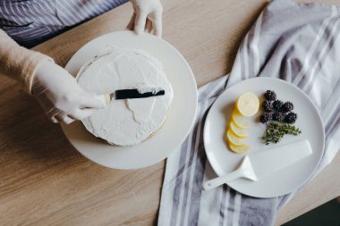 Karantina sırasında üzerinde meyve, böğürtlen, limon ve nane olan limonlu kek pişiren bir ev hanımı manzarası. Ev yapımı limonlu kek tarifi. Evde yemek pişirmek..