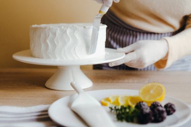 Ev hanımı ev yapımı limonlu kek pişiriyor. İnsan elinin üstünde bıçakla hamur işi pişirmekle meşgul..