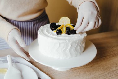 Mutfaktaki ev hanımı karantina sırasında limonlu pastayı meyve, böğürtlen, limon ve nane ile süslüyor. Organik ev yapımı limonlu kek tarifi.