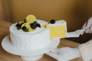 Ev hanımı taze lezzetli bir dilim ev yapımı limonlu pasta alıyor. Limonlu organik kek tarifi..