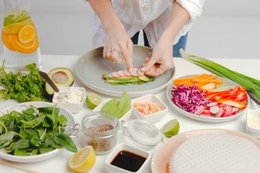 Kadınların elleri börek hazırlıyor, dilimlenmiş turp, fesleğen, salatalık ve tohumları mutfak masasına koyuyor..