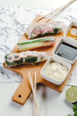 Tahta tabakta servis edilen karides, sebze ve soslu leziz börekler..