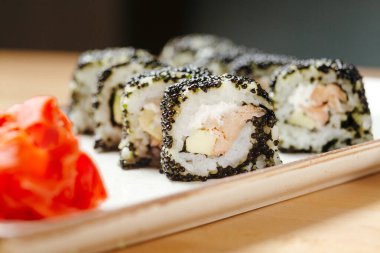 Suşi, California somonunu yuvarla. Qurantine 'de yemek teslimatı. Pirinç, nori, kaplan karidesi, salatalık, avokado, baharat sosu, masago havyarı.