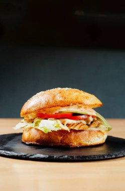 Siyah tabakta domatesli tavuk bifteği burger. Abur cubur. Fast food. Vücut pozitifi. Karantinadaki yiyecekler teslimattan. Menü için fotoğraf.