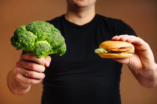 The choice between healthy food broccoli and unhealthy junk food hamburger.