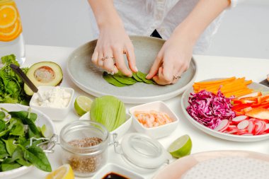 Kadın mutfak masasındaki pirinç kağıdında turp, fesleğen, salatalık ve tohumla börek hazırlıyor..
