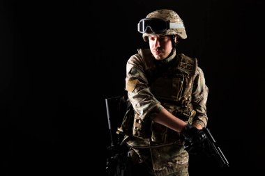 Silahlı bir asker siyah arka planda görevde. Savaş kavramı.