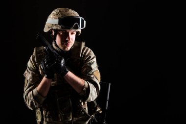 Silahlı bir asker siyah arka planda görevde. Savaş kavramı.
