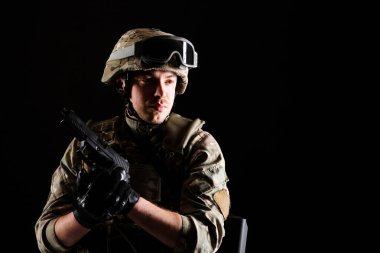 Silahlı bir asker siyah arka planda görevde. Savaş kavramı.