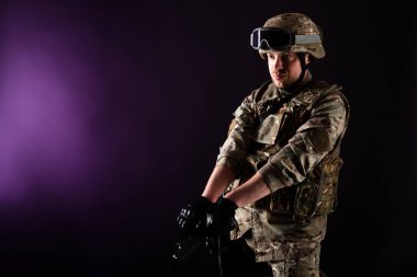 Silahlı bir asker menekşe arka planındaki hedefe nişan alıyor. Silahlı bir savaş erbabı menekşe arkaplanındaki hedefe nişan alır. Savaş kavramı.