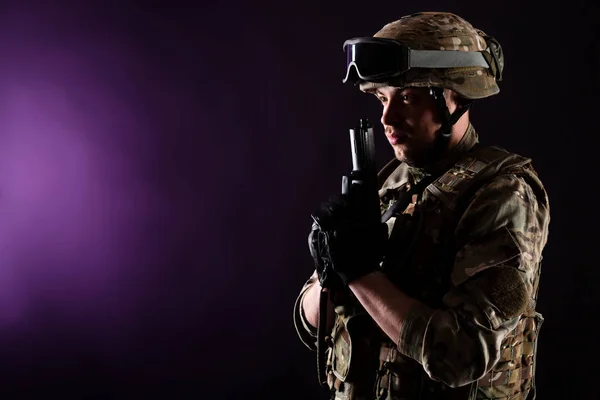 Soldier with gun aims at the target on mission on violet background. Concept of war.
