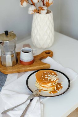 Mutfaktaki beyaz masada kahve makinesinin yanında tuzlu karamel ve fıstıklı gözleme. Karantinada sabah kahvaltısı. Ev yapımı lezzetli krep tarifi..