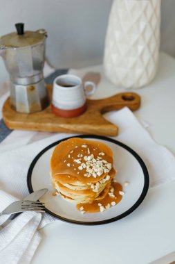 Mutfaktaki beyaz masada kahve makinesinin yanında tuzlu karamel ve fıstıklı gözleme. Karantinada sabah kahvaltısı. Ev yapımı lezzetli krep tarifi..