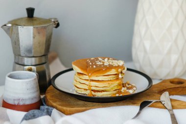 Mutfaktaki beyaz masada kahve makinesinin yanında tuzlu karamel ve fıstıklı gözleme. Karantinada sabah kahvaltısı. Ev yapımı lezzetli krep tarifi..