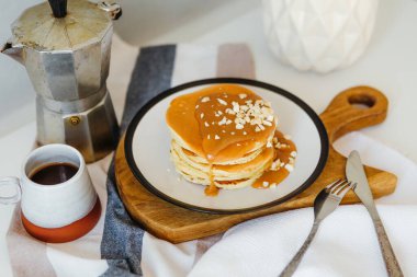 Mutfaktaki beyaz masada kahve makinesinin yanında tuzlu karamel ve fıstıklı gözleme. Karantinada sabah kahvaltısı. Ev yapımı lezzetli krep tarifi..