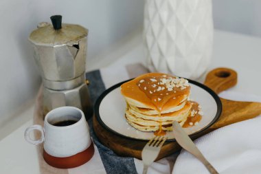 Mutfaktaki beyaz masada kahve makinesinin yanında tuzlu karamel ve fıstıklı gözleme. Karantinada sabah kahvaltısı. Ev yapımı lezzetli krep tarifi..