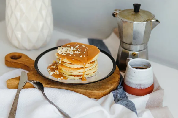 Mutfaktaki beyaz masada kahve makinesinin yanında tuzlu karamel ve fıstıklı gözleme. Karantinada sabah kahvaltısı. Ev yapımı lezzetli krep tarifi..