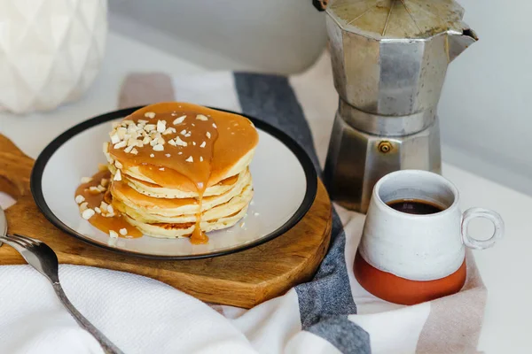 Mutfaktaki beyaz masada kahve makinesinin yanında tuzlu karamel ve fıstıklı gözleme. Karantinada sabah kahvaltısı. Ev yapımı lezzetli krep tarifi..
