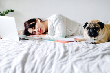 Genç güzel kız çalışırken yoruldu ve evde yatakta uyuyakaldı. Merkez ofis. Tecrit altında çalışma ve öğrenim kavramı.