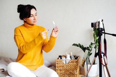 Genç esmer kız güzellik blogcusu kamerada nasıl antiseptik kullanılacağını gösteriyor. Blog çekmenin konsepti. Güzellik ve cilt bakımı.
